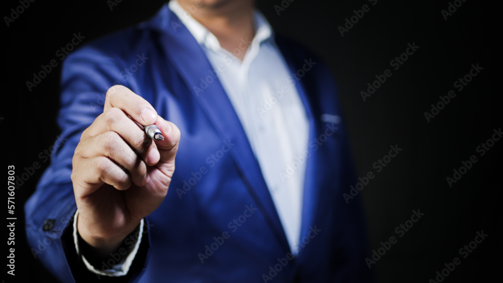 Businessman holding a pen to write on the screen to sign a contract or an agreement on blur background