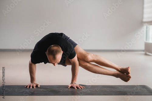 An athletically built man does yoga in the gym on a mat photo