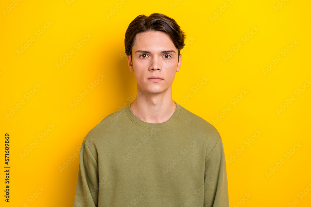 Portrait of serious focused young person calm face green sweater isolated on yellow color background