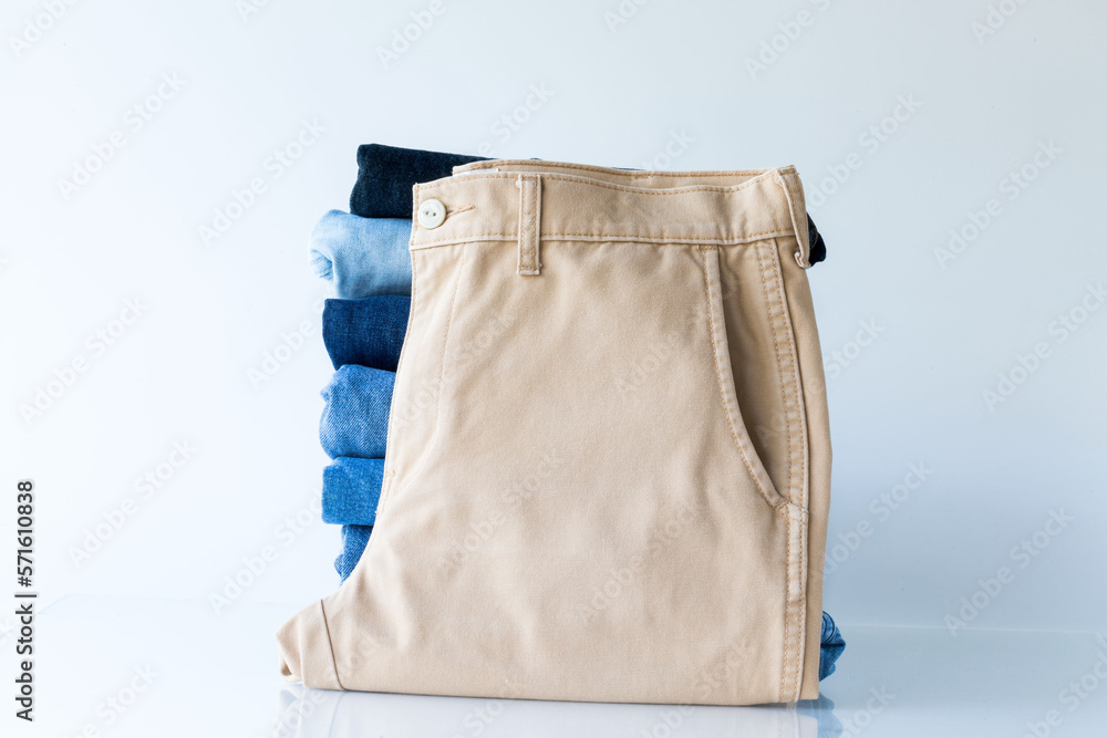 Stack of brown and blue jeans on a white background in shop and supermarket . business jeans concept.. Stack of brown and blue jeans on a white background in shop and supermarket . business jeans concept..