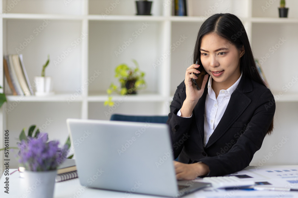 Businesswoman working with documents on laptop in office. The secretary is talking on the mobile phone and analyzing the monthly work schedule. Businesswoman working with documents on laptop in office. The secretary is talking on the mobile phone and analyzing the monthly work schedule.