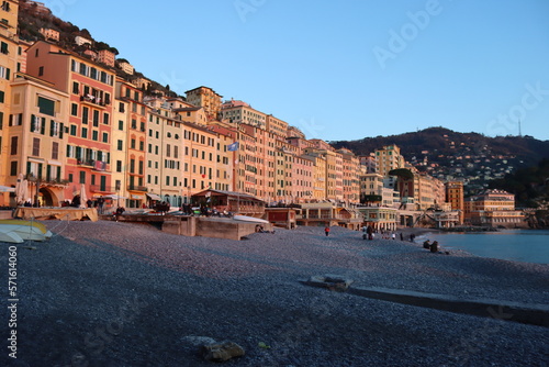 Camogli, Italy - January 27, 2023: Beautiful old mediterranean town at the sunrise time with illumination during winter days. People enjoying the evening at the beach with beautiful sunset background