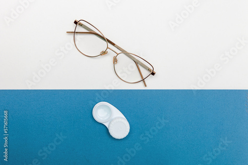 Choice between glasses and contact lenses. Container with contact lenses and glasses on a blue and white background