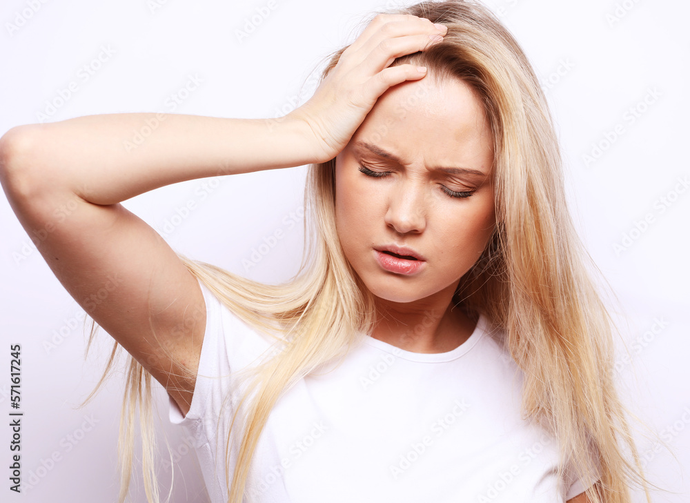 Young woman clutching her head with her palms while suffering from a migraine. Young woman clutching her head with her palms while suffering from a migraine.