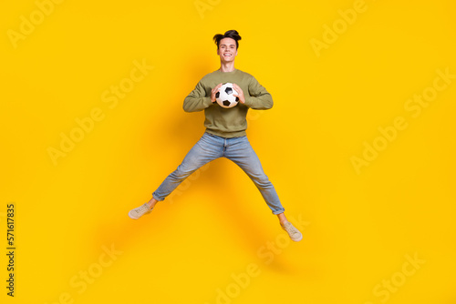 Full body portrait of carefree crazy person jumping hands hold football isolated on yellow color background