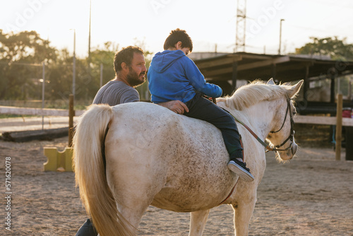 Child with disabilities has an equine therapy session with a physiotherapist.