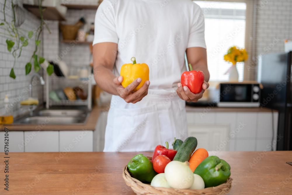 Man holding bell pepper preparing food in kitchen at home. Man holding bell pepper preparing food in kitchen at home.