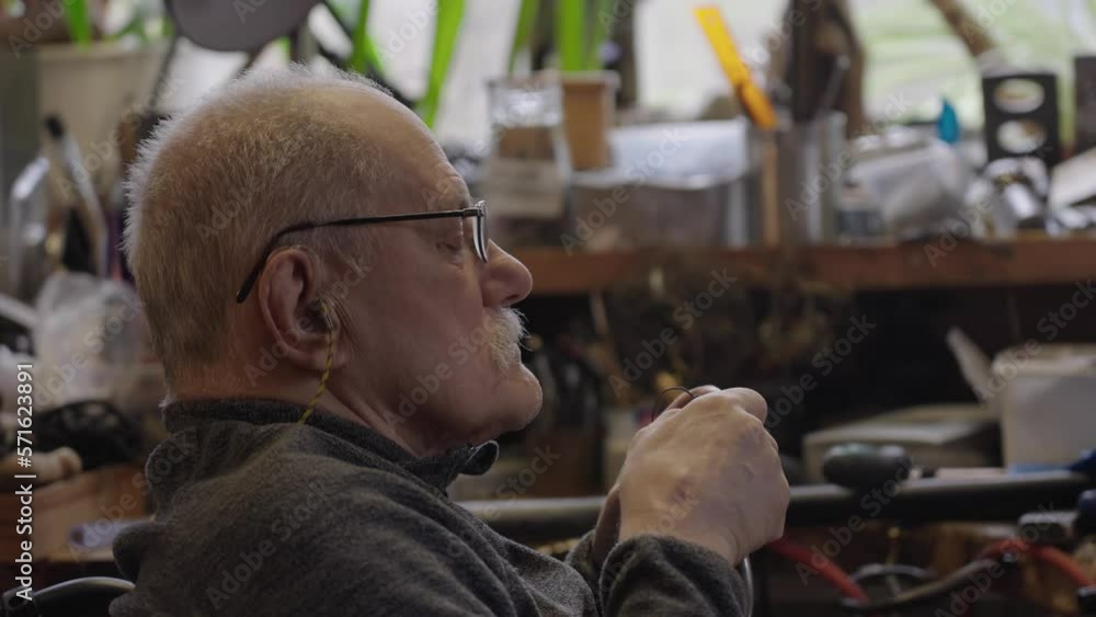 Senior elderly master jeweler in wheelchair works in a workshop Senior elderly master jeweler in wheelchair works in a workshop