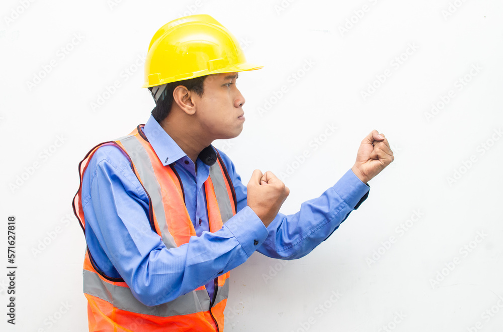 side view of stressed over work concept illustrated by asian male construction worker in blue shirt, orange vest and yellow safety helmet with furious, mad, sad, angry expression. overworked concept side view of stressed over work concept illustrated by asian male construction worker in blue shirt, orange vest and yellow safety helmet with furious, mad, sad, angry expression. overworked concept