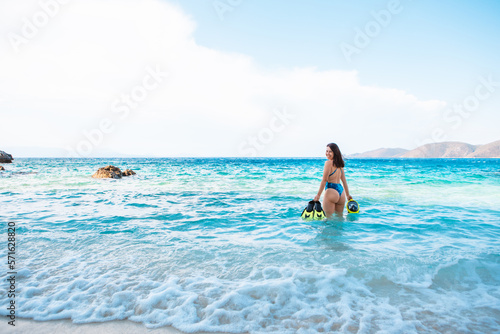 sexy woman in blue swimsuit going to the sea with with flippers and snorkeling mask