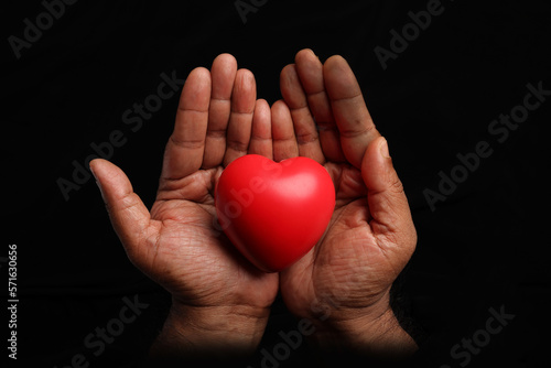 Asian dark skin top view two hand holding making red hart love shape sign on black background