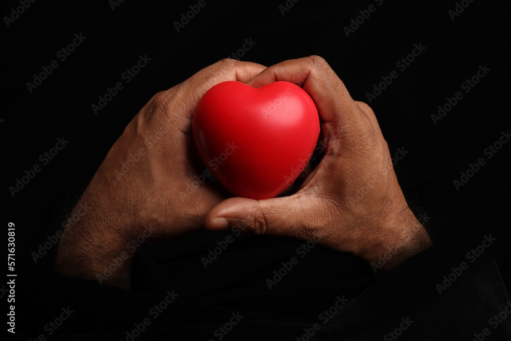 Asian dark skin top view two hand holding making red hart love shape sign on black background Asian dark skin top view two hand holding making red hart love shape sign on black background