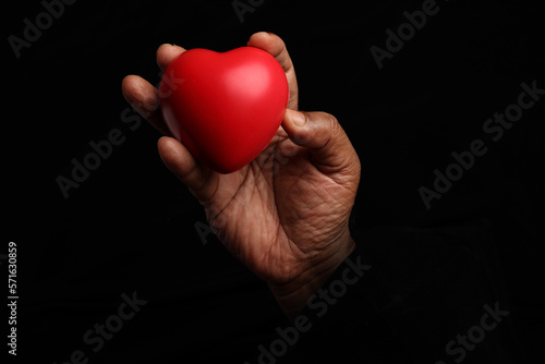 Asian dark skin top view two hand holding making red hart love shape sign on black background