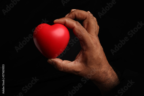 Asian dark skin top view two hand holding making red hart love shape sign on black background