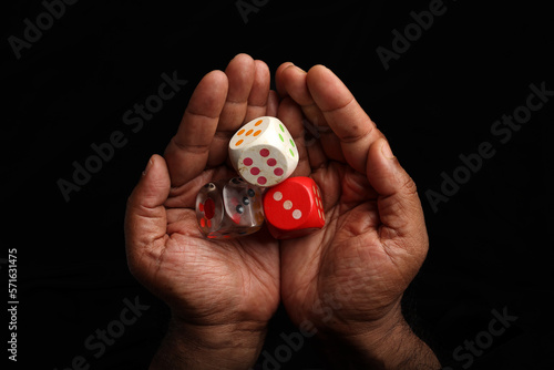 Asian dark skin top view two hand finger holding playing dice gamble luck on black background