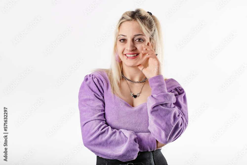 Young woman smiling confident wearing ribbed blouse standing isolated over white background enjoys talking and laughs a lot. He touches his chin with his hand and likes it. Young woman smiling confident wearing ribbed blouse standing isolated over white background enjoys talking and laughs a lot. He touches his chin with his hand and likes it.