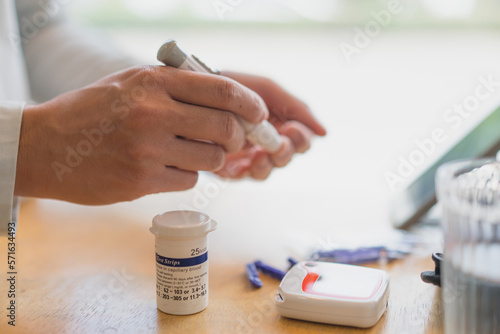young man using blood test kit at home while doing health check . home finger prick blood test . close up  diabetes concept  elderly health care 