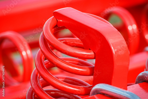 Big and hard red steel spring as part and detail of industrial or agricultural machine