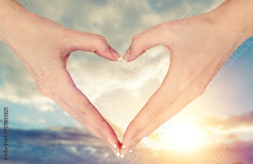 Human hands in heart shape on sky background