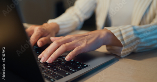 Close-up Young Asia businesswoman wear formal sit front of desk with laptop computer focus finger typing on keyboard made report work in cozy living room indoor at home night. Overtime work concept.
