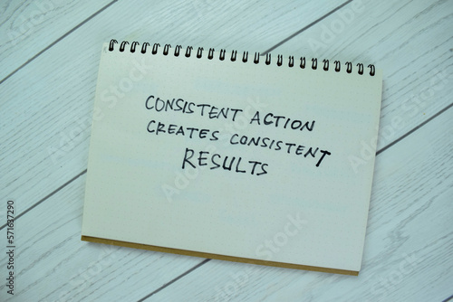 Concept of Consisten Action Creates Consistent Results write on book isolated on Wooden Table. photo