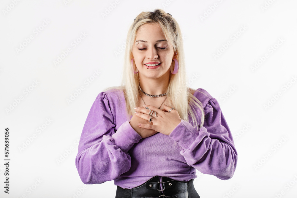 Young woman smiling confident standing isolated over white background hold hands on heart chest feel grateful and thankful. Show gratitude, love and care, pray or visualize. Religion, faith concept. Young woman smiling confident standing isolated over white background hold hands on heart chest feel grateful and thankful. Show gratitude, love and care, pray or visualize. Religion, faith concept.