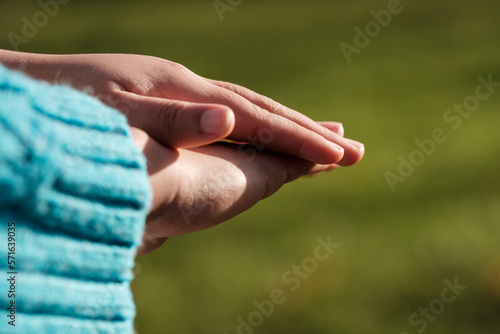 Close-up of female hands touching each other outside.