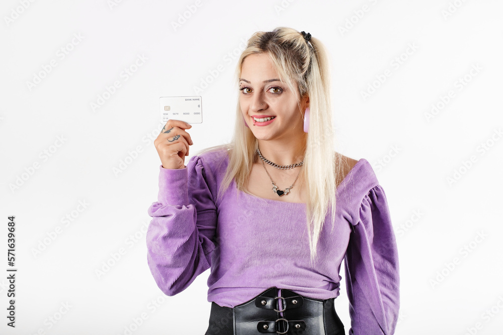 Young woman confident standing isolated over white background holding a credit or debit card looks at the camera and poses. Finds shopping very attractive. It offers a promotion. Advertising image. Young woman confident standing isolated over white background holding a credit or debit card looks at the camera and poses. Finds shopping very attractive. It offers a promotion. Advertising image.