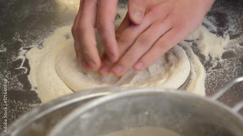 Close-up of the chef's hands form a round pizza base from the dough with his hands. The pizzeria chef kneads the dough for traditional Italian pizza. Close-up of the chef's hands form a round pizza base from the dough with his hands. The pizzeria chef kneads the dough for traditional Italian pizza.