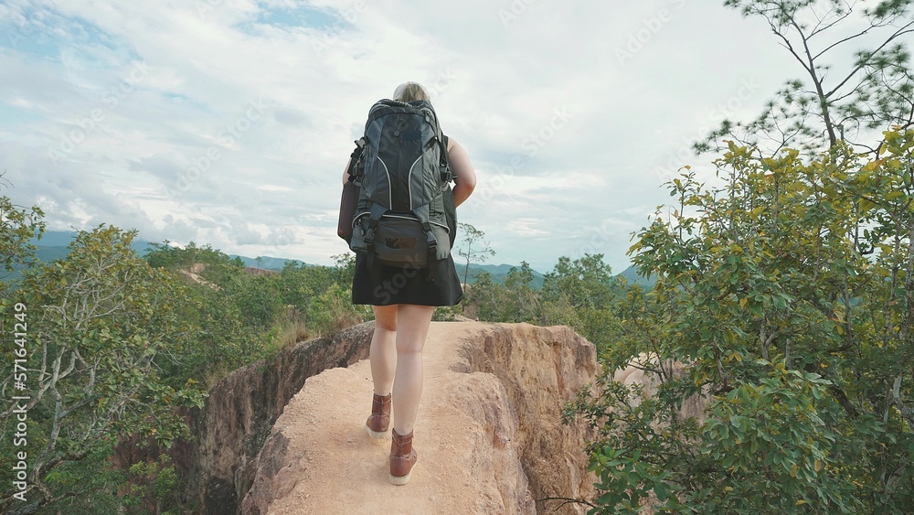 Woman traveler carrying a backpack walking in dangerous rocky top the mountain. Travel adventure tourist