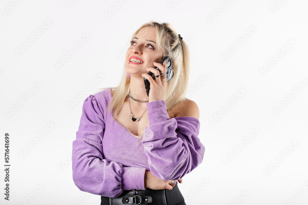 Young woman smiling confident wearing ribbed blouse standing isolated over white background laughing, looks up at the copy space and talks on the phone. Daydreaming. Young woman smiling confident wearing ribbed blouse standing isolated over white background laughing, looks up at the copy space and talks on the phone. Daydreaming.