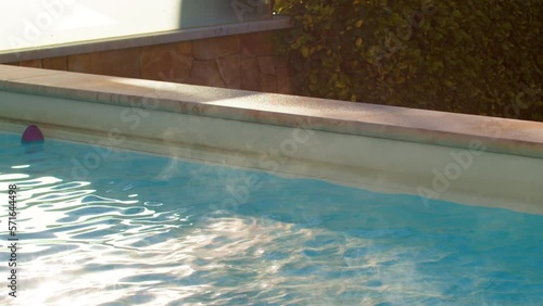 Slow motion static shot of steam rising from rippling hot water in pool on sunny summer day photo