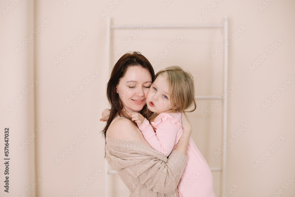 Woman in light clothes have fun with cute child baby girl 3 years old. Mommy little kid daughter on beige background studio portrait. Mother's Day love family parenthood childhood concept