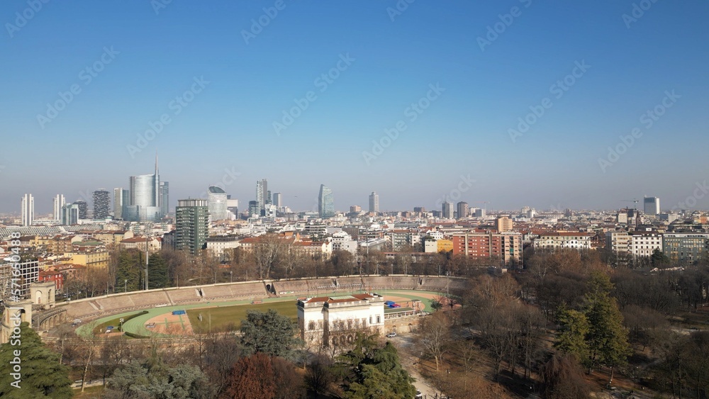 EUROPE, ITALY MILAN 2023 - Drone aerial view  in Sempione park - Arena old soccer Stadium  and the new skyline of the city in downtown - Old architecture and new modern skyscrapers in Gae Aulenti 