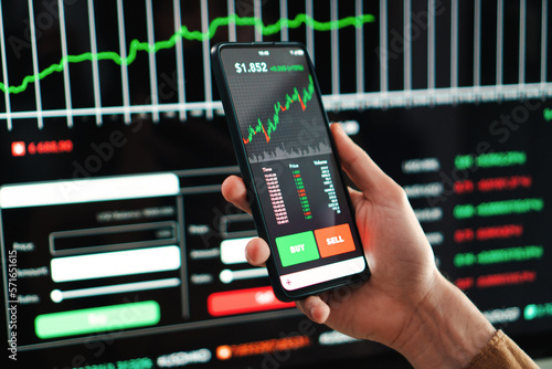 Crypto trader broker using a cell phone financial app to buy or sell shares of stock market. Investment concept. Caucasina hand holding a smartphone with banking blockchain application on the screen