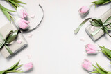  festive layout with tulips and a gift with green ribbons on a grey background. copy space. top view. flat lay. concept of mother's day, valentines day, eighth of march