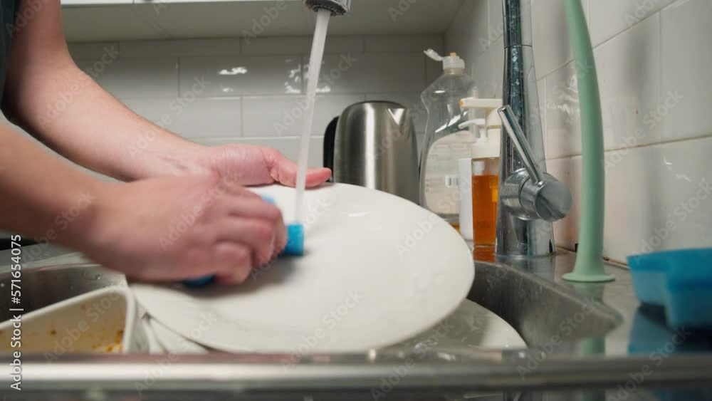 Male housewife washes a plate under running water in the sink in a modern kitchen. slow motion video of housewife using natural dishwashing detergent Male housewife washes a plate under running water in the sink in a modern kitchen. slow motion video of housewife using natural dishwashing detergent