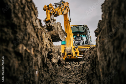 A worker in bulldozer is moving soil and making hole on construction site. photo