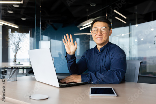 Canvas Print Portrait of a young handsome Asian male programmer working in the office at a laptop