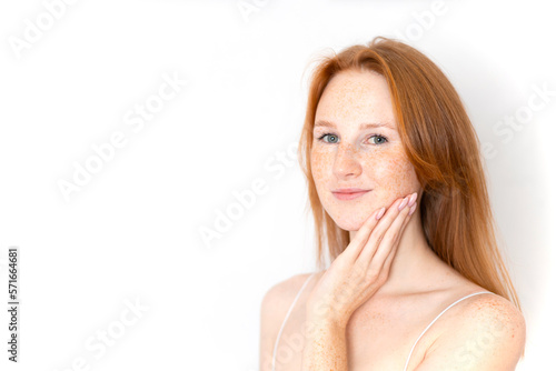 A natural portrait of a beautiful young red-haired girl on a white background. Light makeup. Self-care. freckles. Space for text.