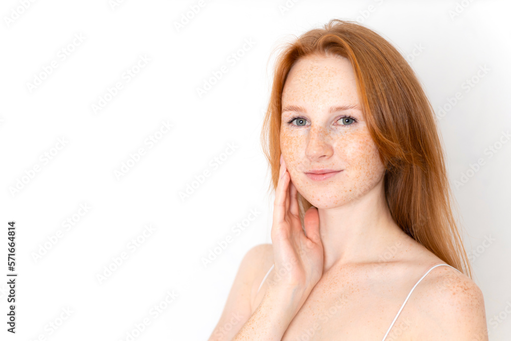 Obraz premium A natural portrait of a beautiful young red-haired girl on a white background. Light makeup. Self-care. freckles. Space for text.