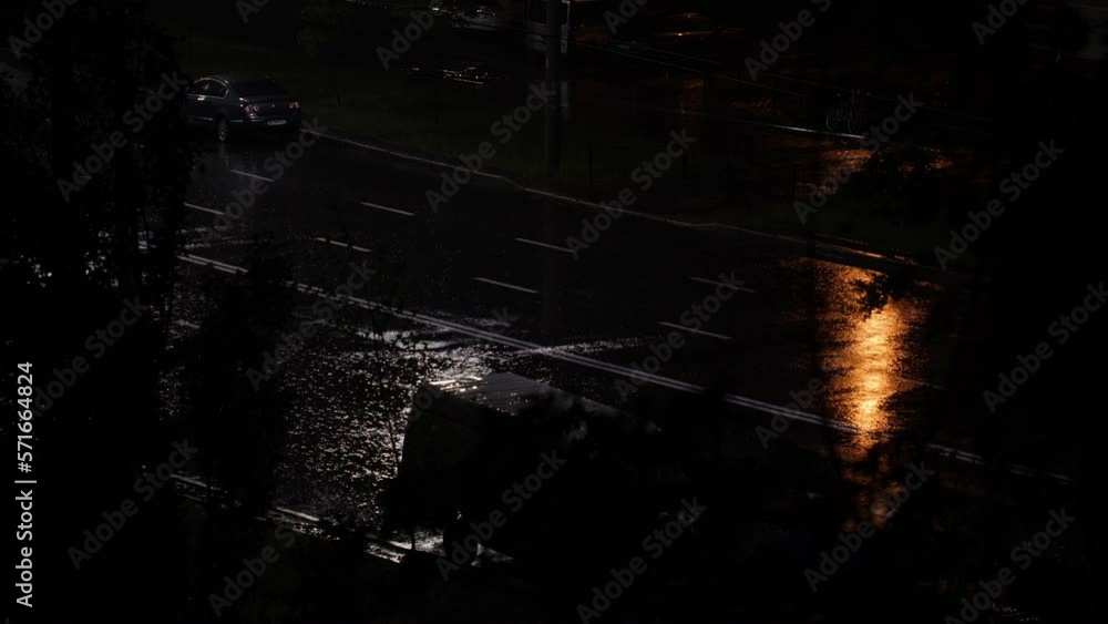 Night road in the rain. Cars on the highway in bad weather. A heavy downpour falls on a city road in the moonlight. Spray flying from under the wheels of cars. The moon path is reflected in puddles Night road in the rain. Cars on the highway in bad weather. A heavy downpour falls on a city road in the moonlight. Spray flying from under the wheels of cars. The moon path is reflected in puddles