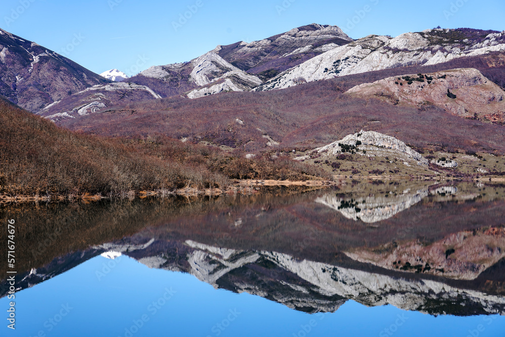 Obraz premium View since the Viewpoint of the porma reservoir, in the province of leon, on a sunny day with the Susarón peak and mountains reflected in the water of the reservoir. Castilla y Leon, Spain.