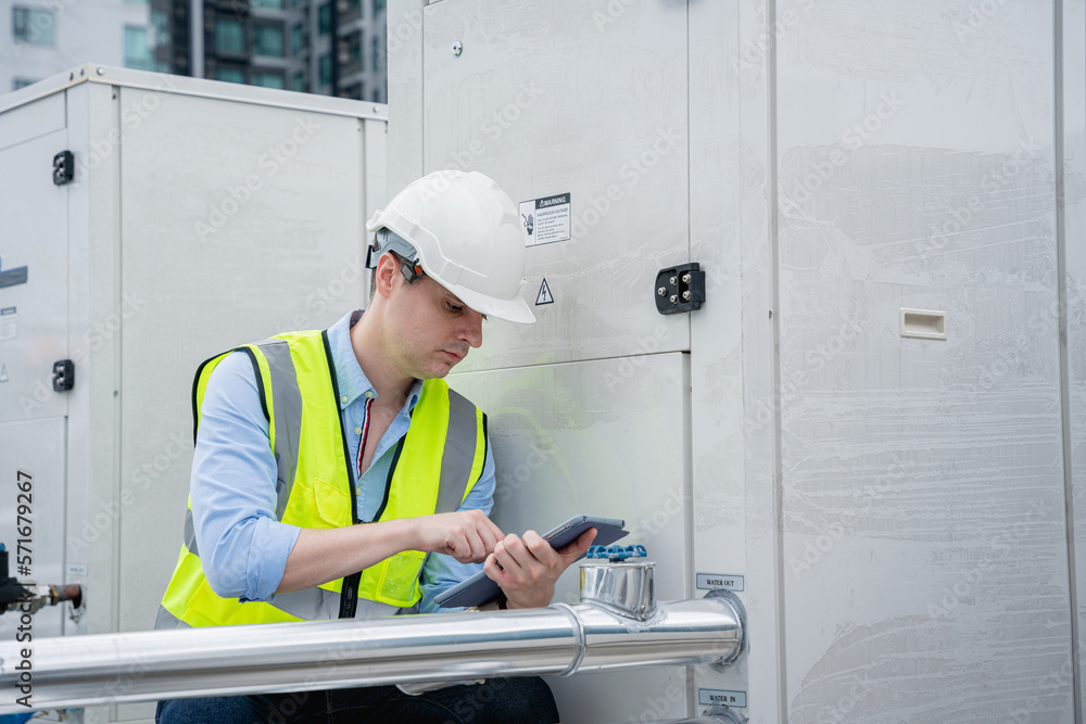 The engineer is inspecting the cooling tower air conditioner in a large industrial building to manage the airflow. The engineer is inspecting the cooling tower air conditioner in a large industrial building to manage the airflow.