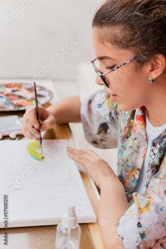 Creadora en acción: joven de origen latino pintando con pincel sobre lienzo. photo