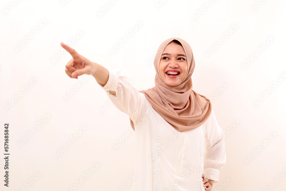 Young asian muslim woman pointing sideways while laughing. Isolated on white background Young asian muslim woman pointing sideways while laughing. Isolated on white background