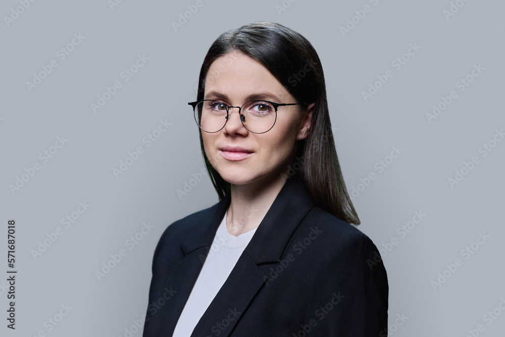 Smiling young business woman looking at camera on grey background Smiling young business woman looking at camera on grey background