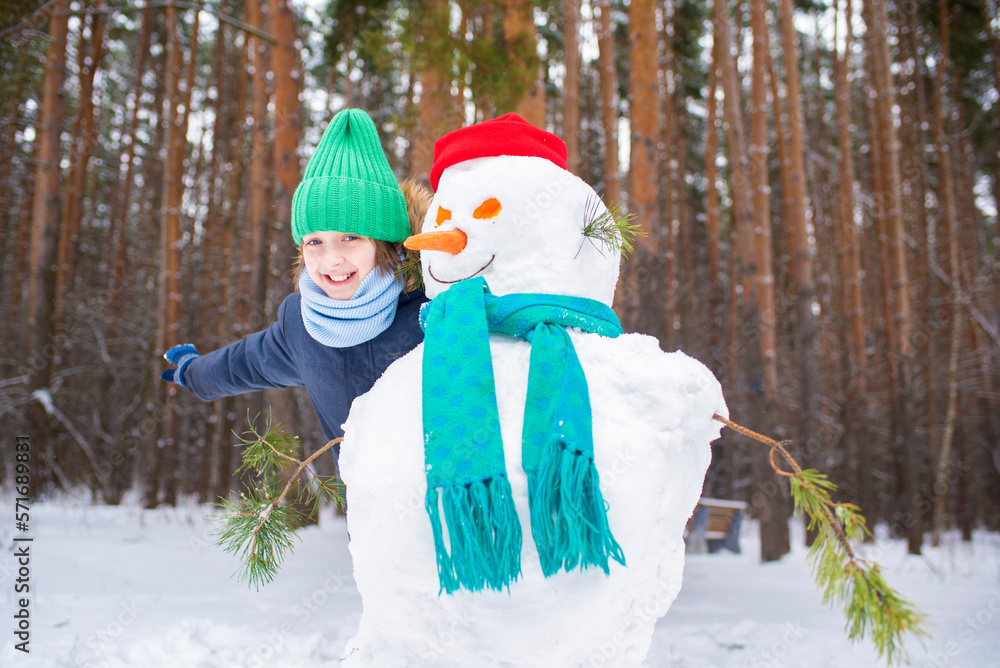 a boy peeks out from behind a snowman, a happy child plays hide and seek in the winter forest a boy peeks out from behind a snowman, a happy child plays hide and seek in the winter forest