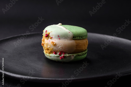 Beautiful tasty macaron with filling and fruit flavor on a black plate