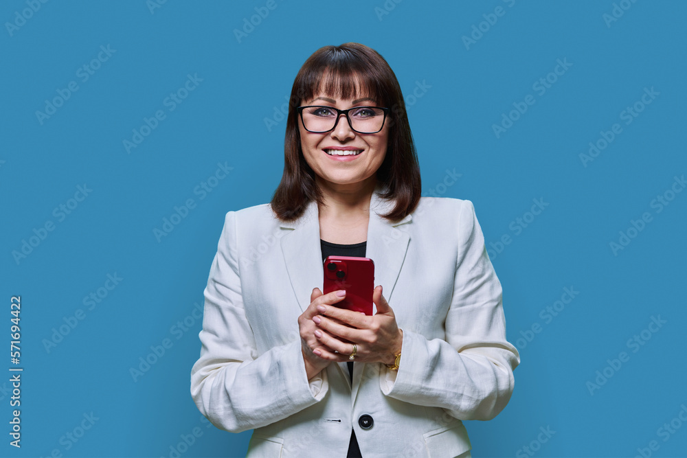 Portrait of middle aged business woman with phone on blue background Portrait of middle aged business woman with phone on blue background